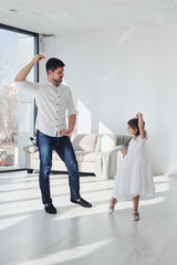 Fototapeta premium Happy father with his daughter in dress learning how to dance at home together