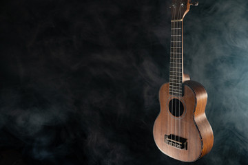 Fototapeta na wymiar Hawaii ukulele guitar isolated against black background with smoke