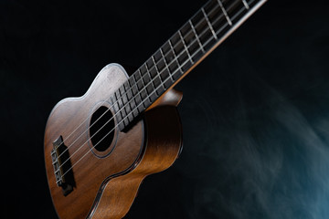 Fototapeta na wymiar Hawaii ukulele guitar isolated against black background with smoke