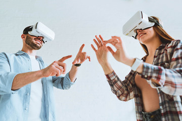 Young happy couple having fun with VR goggles headset glasses.