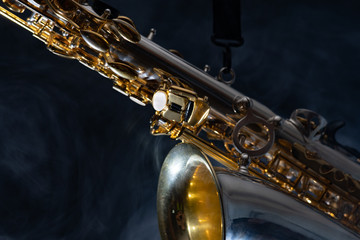 Golden shiny alto saxophone on black background with smoke. copy space