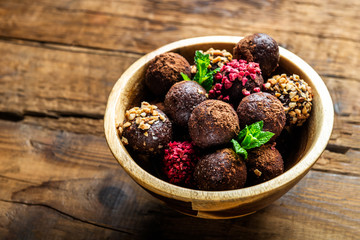 Various Homemade Raw Vegan Truffles or Energy Balls, such as Almond and Cacao, Dark Chocolate and Hazelnut Butter inside wooden Plate and Rustic Background