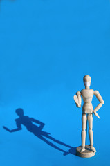 A figure of a man made of wood in a medical mask holds his hands up, warning of danger. Coronavirus, pandemic and epidemic concept