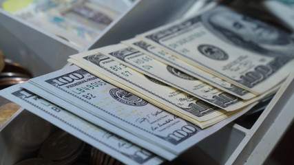 American dollars stacked on a dark background, in a wallet, in a cash drawer