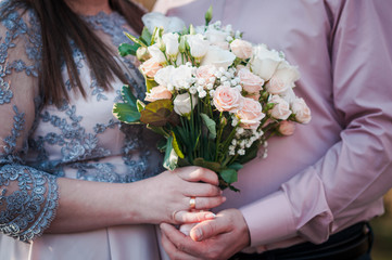 Groom and bride holding colorfull wedding bouquet in the hand