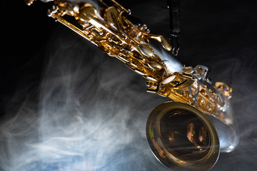 Golden shiny alto saxophone on black background with smoke. copy space