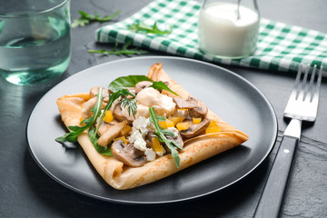 Delicious breakfast with thin pancakes on black table