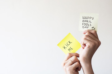 April 1 is day of fools.Funny day.April fish.Practical jokes.Inscriptions on paper.Stickers in hands.Trick at work.Cheerful colleagues.Colored stickers with inscriptions.Place for text.Hands isolated