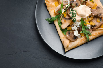 Delicious breakfast with thin pancakes on black table, top view. Space for text