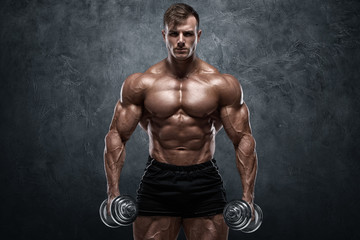 Muscular man with dumbbells on wall background. Strong male naked torso abs - obrazy, fototapety, plakaty