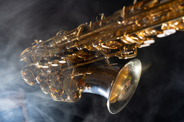 Golden shiny alto saxophone on black background with smoke. copy space