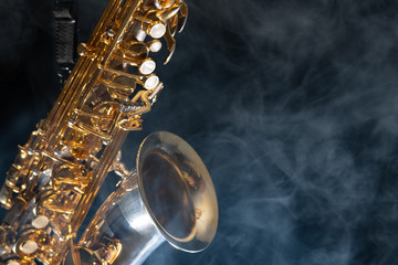 Fototapeta premium Golden shiny alto saxophone on black background with smoke. copy space