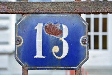 A house number plaque, showing the number thirteen (13)