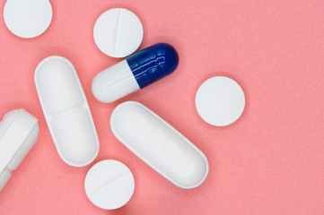 Various white and blue pills on pink background with copy space. Different medical drugs . 