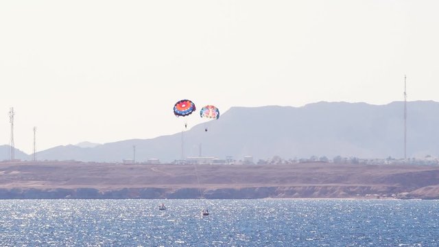 Timelapse tourists on a parachute over the sea. Parasailing in the red sea. Holidays concept 4k