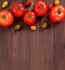 Sweet cherry tomatoes of different colors and fresh tomatoes on brown wooden background with copy space. Juicy vegetables, bio food