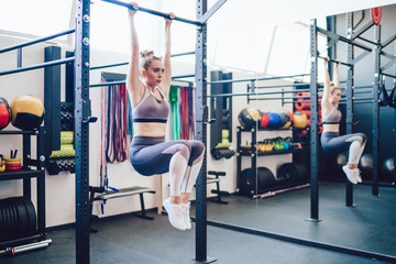 Athletic woman hanging on horizontal bar training abs