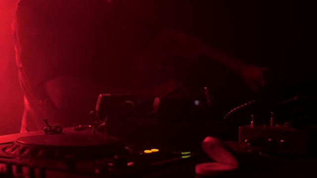 DJ plays a set at the party. Musical equipment. Light from party lights.