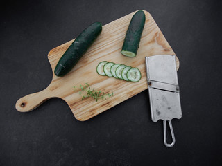 Sliced cucumber with mandoline on a wooden board