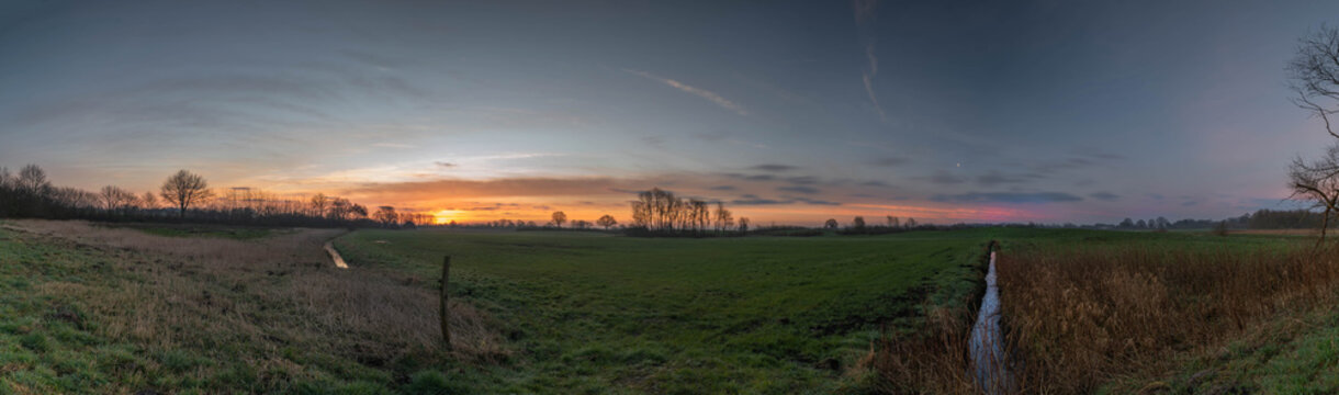 Panorama of sunset sunrise over field or meadow on the countryside © snapshotfreddy