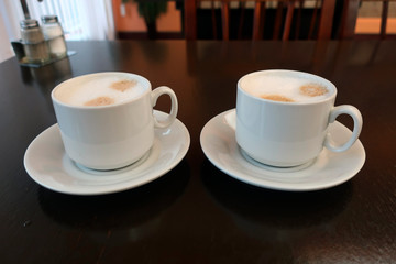 two cups of coffee latte on a table in a restaurant