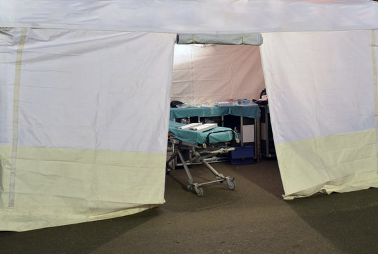 Empty Hospital Field Tent For The First AID, A Mobile Medical Unit Of Red Cross For Patient With Corona Virus. Interior Camp Room With Folding Camp Bed For People Infected With An Epidemic. Covid-19.	
