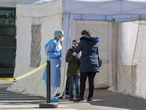 Alert pandemic Covid-19. Triage hospital field tent for the first AID, a mobile medical unit for patient infected with Corona Virus. Doctors with protective masks check a little girl at the entrance.