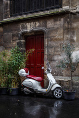 The scooter parked near red door.