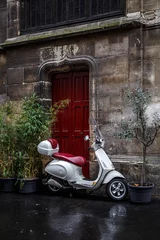 Foto op Plexiglas The scooter parked near red door. © 9parusnikov
