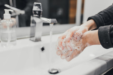 Washing hands with antibacterial soap at home bathroom for coronavirus prevention. Coronavirus pandemic protection by washing hands frequently. Hygiene to stop spreading coronavirus.