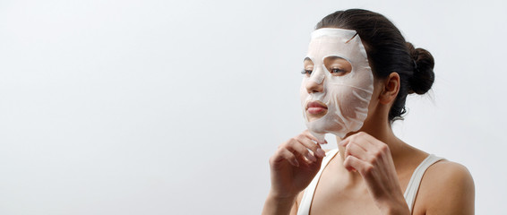 Pretty dark-haired woman adjusting facial sheet mask, skin care concept