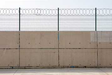  Razor wire with its sharp steel barbs on top of a concrete wall