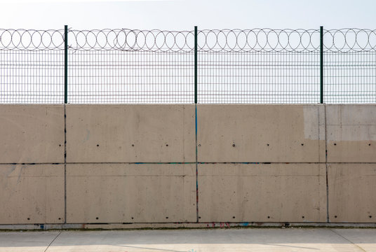  Razor wire with its sharp steel barbs on top of a concrete wall