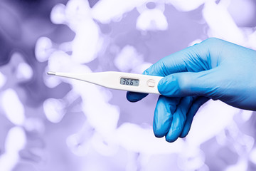 Medical worker in gloves holding an electronic thermometer in his hand on background