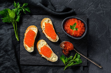 Sandwiches with salmon red caviar. Black background. Top view