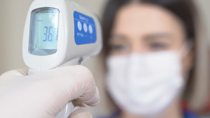  Taking woman 's temperature with thermometer to find infected by coronavirus, Covid-19. Close up shot.