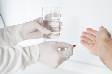 The doctor administers the antibiotic and glass of water to the patient