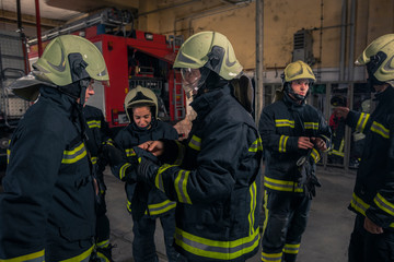 Firemen preparing for emergency service. Firefighters putting on gloves.