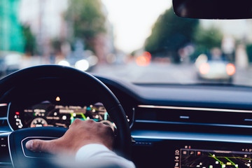Cropped image of male steering automobile car on speedway signaling during rush hour in metropolis,...