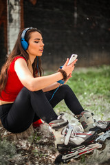 Fototapeta na wymiar Girl sitting on the stone while listening music on headphones