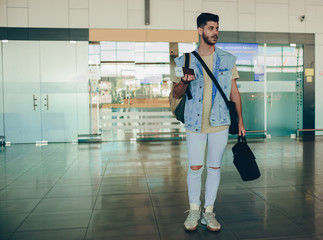 Happy traveler man is waiting for his flight at the airport