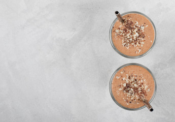Smoothie from dates, nuts, chocolate in a glass on a light gray background top view