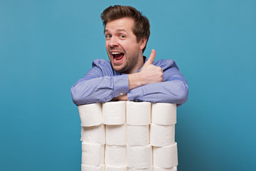 Excited happy caucasian man holding a pile of toilet paper showing thumb up