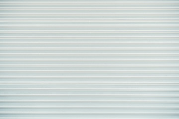 A bright white seamless texture of a surface of an outdoor metal vertical folding door from a street shop or a garage, consists of thick horizontal stripes with rare barely visible rivets