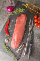 Langet - raw, large piece of meat on slate, the back muscle of beef. Red beef meat with texture and...