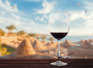 Glass of red wine against the backdrop of the sea beach and balloons