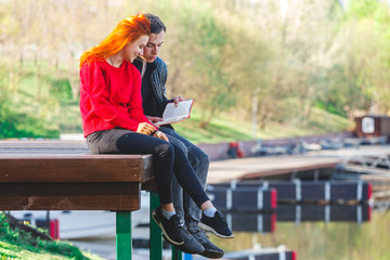 Young man and girl students reading a book