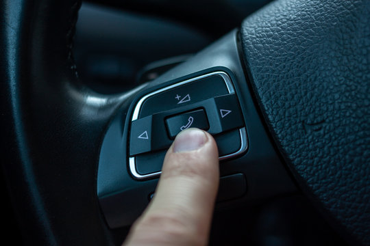 finger pressing answer button on steering wheel