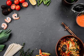 Chinese dishes in a clay plate on a black concrete background with ingredients for delivery