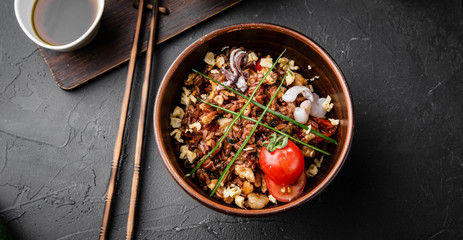 Chinese dishes in a clay plate on a black concrete background with ingredients for delivery